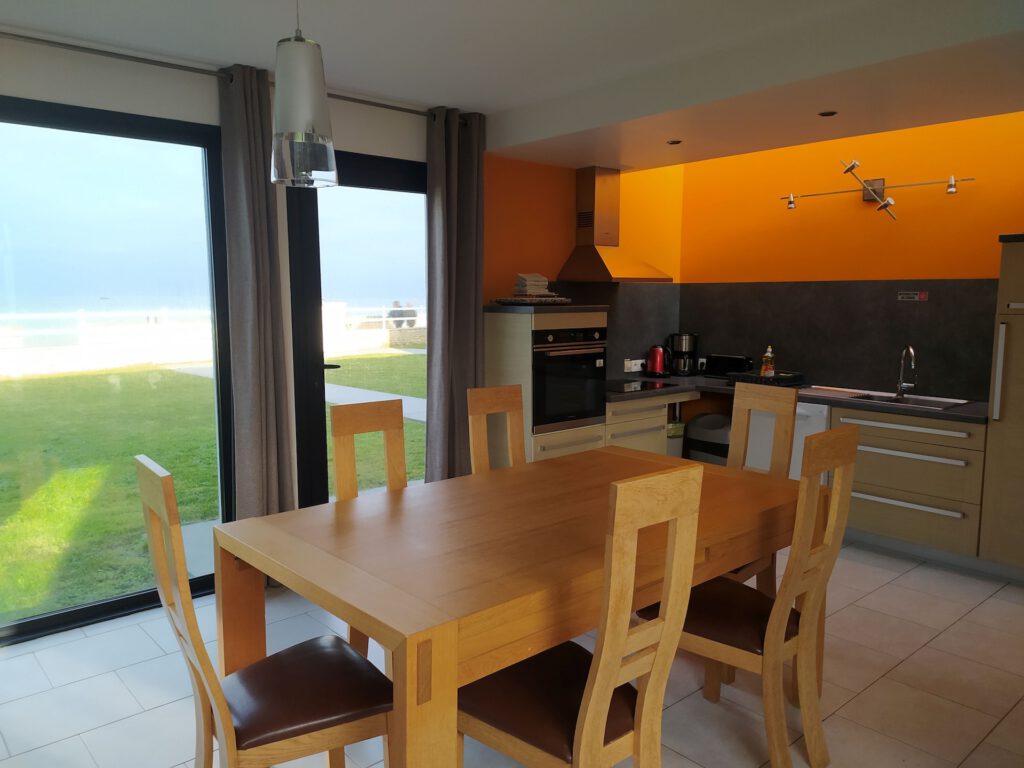 Interiør af et moderne sommerhus med udstyret køkken og havudsigt, beliggende ved havet i Asnelles.